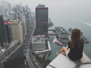 woman sitting on top of building overlooking on city by the bay during daytime
