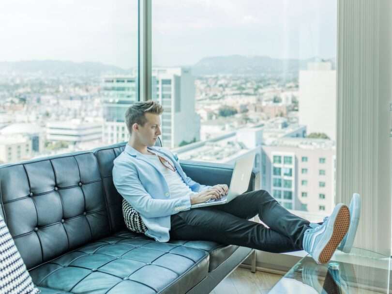 man sitting on sofa while using laptop